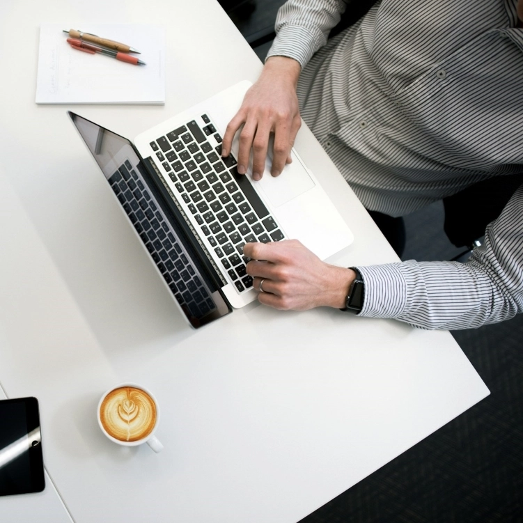 Person working on a laptop with a cup of coffee nearby.